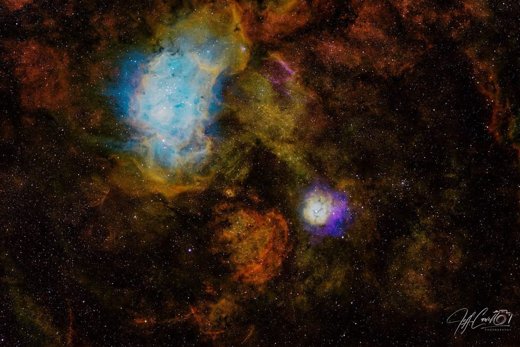 A deep-sky field of gold and blue nebulae among dense stars
