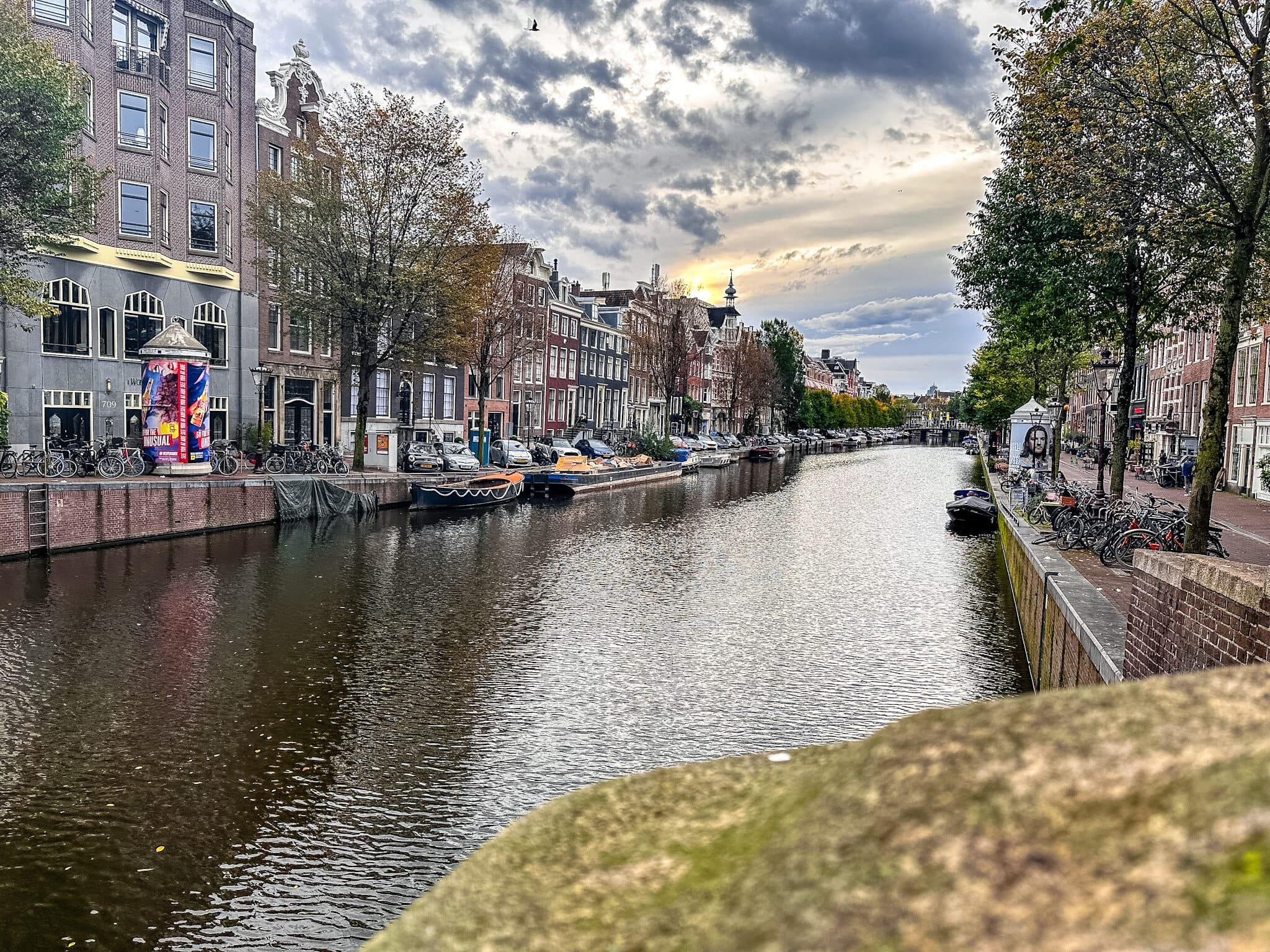 Gabled houses and boats along an Amsterdam canal under a heavy sky